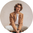blonde boy with brown jacket sitting